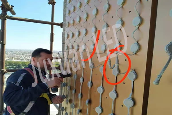 Engineers installing LED pixel lights on a building facade